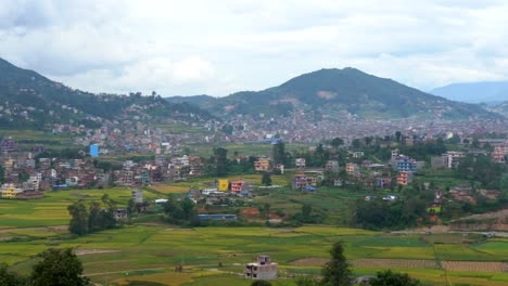 A-panning-view-of-a-beautiful-lush-green-valley-with-towns-and-rice-paddies-under-a-cloudy-sky