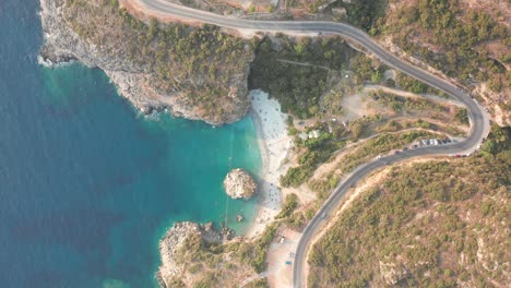 Bird's-eye-view-of-a-curvy-road-passing-by-foneas-beach,-Greece