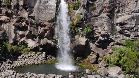 Rugged-cliff-waterfall-lands-in-small-green-rocky-pool,-Mt-Ngauruhoe