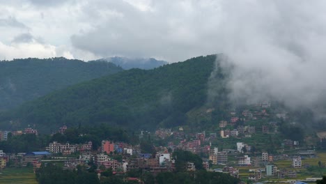 Clouds-drifting-over-the-mountains-and-into-the-lush-green-valley-and-over-the-small-town-timelapse