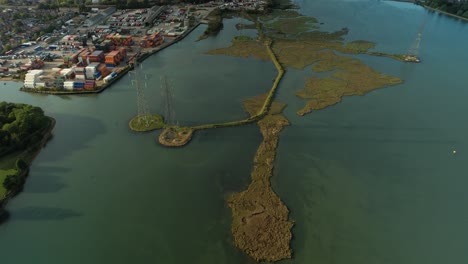 Aerial-View-Of-High-Voltage-Transmission-Towers-On-River-Test-Near-Logistics-Terminal-In-Port-City-Of-Southampton-In-UK
