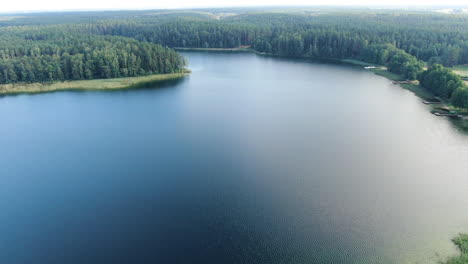 Vast-lake-surface-with-sky-reflection-in-Lithuania,-high-angle-drone-view