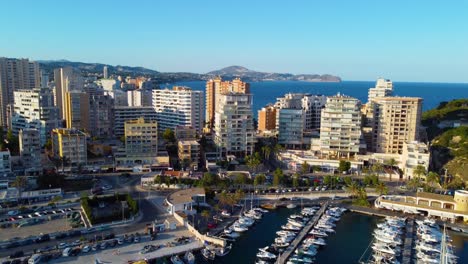 Filmischer-Rotierender-Drohnenclip-über-Einem-Jachthafen-Mit-Hotels-Und-Resorts-Im-Hintergrund-In-Der-Küstenstadt-Calpe-In-Spanien