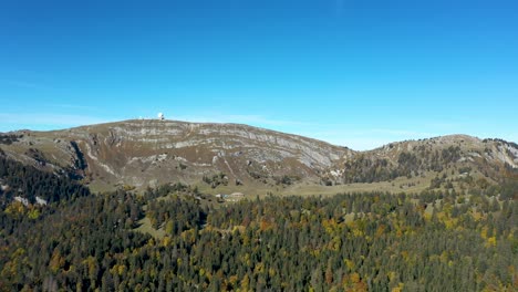 Eine-Drohne-Fliegt-über-Einen-Alpenwald-Mit-Blick-Auf-Einen-Großen-See-Und-Im-Fernen-Dunst-Ein-Majestätischer-Blick-Auf-Das-Massiv-Des-Mont-Blanc-Und-Die-Hohen-Gipfel-Der-Schweizer-Und-Französischen-Alpen