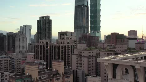Filmischer-Luftsockel,-Der-Das-Stadtbild-Und-Das-Höchste-Gebäude-Von-Taipeh-101-In-Der-Innenstadt-Von-Xinyi,-Taiwan,-Bei-Goldenen-Stunden-Des-Sonnenuntergangs-Einfängt