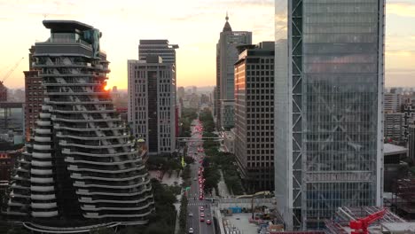 Filmische-Luftaufnahme,-Drohne-Fliegt-über-Der-Songgao-Road-Mit-Hochhaus-Wolkenkratzern-Und-Apartmentkomplex-Daneben-Bei-Sonnenuntergang-In-Der-Innenstadt-Von-Xinyi-District,-Taipei-City,-Taiwan