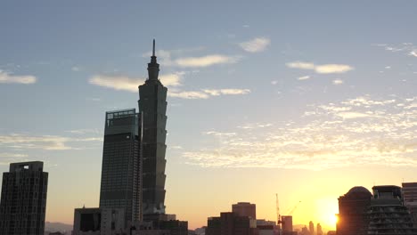Cinematic-aerial-tracking-shot-capturing-the-cityscape-and-tallest-building-Taipei-101-in-downtown-Xinyi-district,-Taiwan,-at-sunset-golden-hours