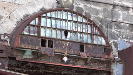 Rusted-arched-window-with-cracked-glass