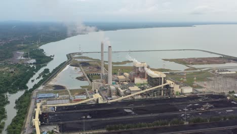 Drone-fly-around-coastal-coalfield,-industrial-ultra-supercritical-coal-fired-power-plant-with-smokes-raising-from-chimney-located-at-lekir-bulk-terminal-jalan,-teluk-rubiah,-manjung,-perak,-malaysia