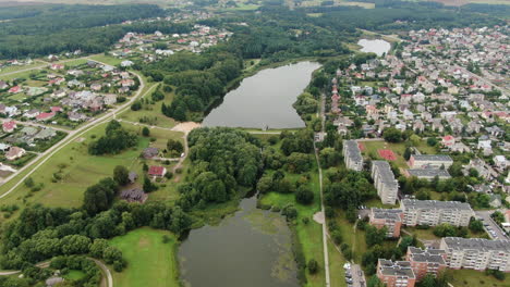 Central-park-of-Jonava-with-small-water-dam-and-living-district,-aerial-drone-view