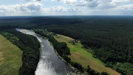 Beautiful-small-homestead-built-near-river-Nemunas-and-forestry-landscape,-aerial-drone-view