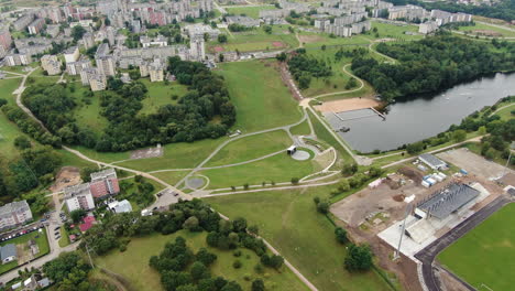 Central-park-of-Jonava-city-with-football-field-and-old-block-apartment-buildings,-fly-over-view