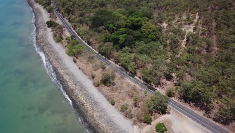 Drone-aerial-Slow-pan-up-to-reveal-mountain-by-a-tropical-beach-and-road