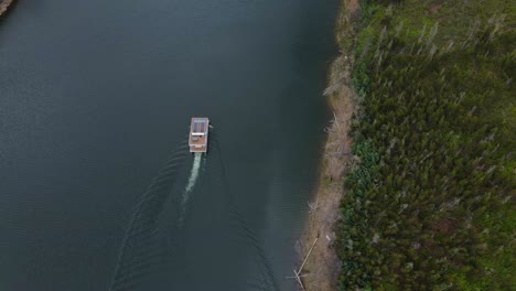 Luftaufnahme-Eines-Solarbootes,-Das-Entlang-Eines-Kiefernwaldes-Im-Fluss-Zêzere-In-Portugal-Segelt