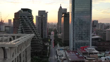 Cinematic-aerial-dolly-in-shot,-drone-flying-above-Songgao-road-with-high-rise-skyscrapers-and-apartment-complex-alongside-at-sunset-in-downtown-Xinyi-district,-Taipei-city,-Taiwan