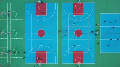 Overhead-view-capturing-people-playing-basketball-in-multipurpose-sports-court,-creative-aerial-shot