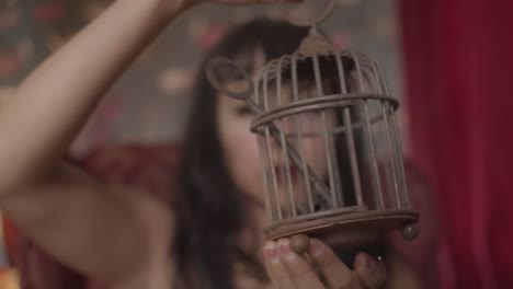 Close-up-video-of-a-woman-with-the-dark-red-lipstick-spinning-a-small-metal-cage-with-a-large-key-inside