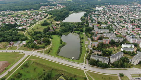 Small-water-ponds-near-big-living-district-with-private-and-apartment-buildings-of-Jonava,-aerial-drone-view