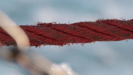 Red-Rope-Of-A-Sailing-Vessel-With-Sea-Waves-Splashing-In-Background