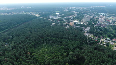 City-of-Druskininkai-surrounded-by-dense-forest,-aerial-drone-view