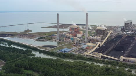 Aerial-shot-of-coastal-coalfield,-industrial-ultra-supercritical-coal-fired-power-plant-with-smokes-raising-from-chimney-located-at-lekir-bulk-terminal-jalan,-teluk-rubiah,-manjung,-perak,-malaysia