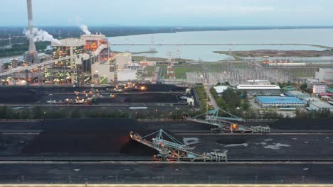 Tracking-shot-across-coalfield-and-industrial-ultra-supercritical-coal-fired-power-plant-with-smokes-raising-from-chimney-located-at-lekir-bulk-terminal-jalan,-teluk-rubiah,-manjung,-perak,-malaysia