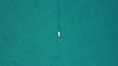 Overhead-drone-clip-of-an-athlete-paddleboarding-on-SUP-board-in-the-middle-of-the-tropical-ocean-in-Calpe,-Spain