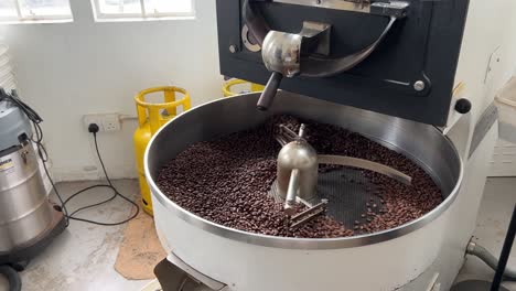 Production-warehouse-factory-shot-of-food-and-beverage-industry,-aromatic-specialty-coffee-beans-on-cooling-and-mixing-tray-to-reduce-the-heat-evenly-after-roasting