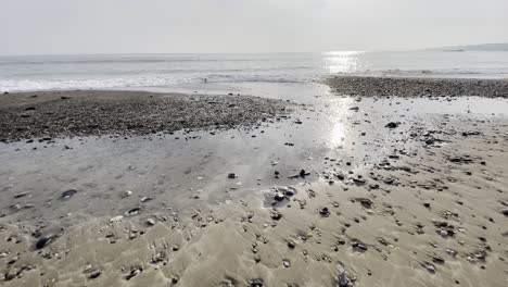Low-Winkel-Aufnahmen-Von-Wellen,-Die-über-Sand-An-Einem-Strand-Kreuzen