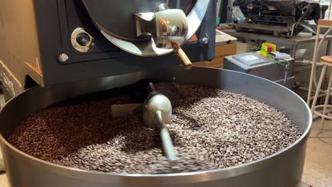 Coffee-production,-close-up-shot-of-roasted-beans-spinning-and-rotating-on-cooling-tray,-warehouse-factory