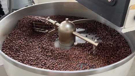 Specialty-coffee-beans-spinning-on-cooling-and-mixing-tray-to-reduce-the-heat-evenly-after-roasting,-production-warehouse-factory-shot-of-food-and-beverage-industry,-close-up-shot