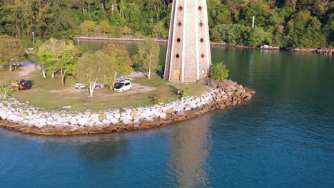 Cinematic-aerial-elevation-shot,-drone-flyover-historical-perdana-quay-light-house-located-on-a-promontory-at-the-entrance-to-telaga-harbor-marina-at-langkawi-island,-kedah,-archipelago-of-malaysia