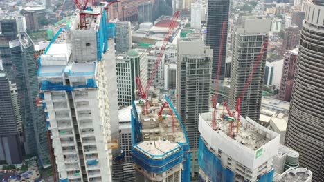 Cinematic-elevation-shot-capturing-various-high-rises-skyscrapers-under-construction,-tilt-up-reveals-downtown-kuala-lumpur-cityscape-with-the-tallest-building-merdeka-118-in-the-skyline