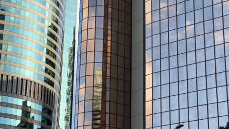 Corporate-buildings-exterior-with-reflective-glass-windows-reflecting-beautiful-sky-and-clouds-at-downtown-metropolitan-area-of-Brisbane-city,-Queensland,-QLD,-close-up-panning-shot