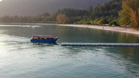 Low-level-drone-fly-around-capturing-local-traditional-fisherman-and-fishing-boat-returning-to-the-shore-at-langkawi-island,-kedah,-archipelago-of-malaysia