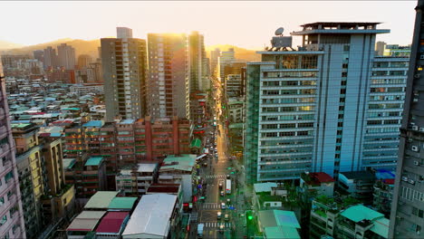 Aerial-flight-between-skyscraper-apartments-and-traffic-on-road-of-Taipei-City-at-sunset