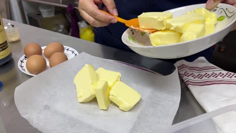 Abmessen-Der-Genauen-Buttermenge-Für-Backrezept,-Auflegen-Auf-Die-Küchenwaage-Mit-Backpapier-Und-Spachtel,-Nahaufnahme