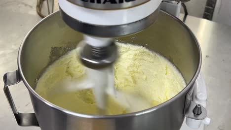 Beating-batter,-cake-mixtures-in-heavy-duty-electric-mixer,-tilt-down-close-up-shot-at-commercial-kitchen-setting