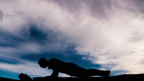 Powerful-silhouette-of-a-fit-male-doing-pushups-against-a-dramatic-sky