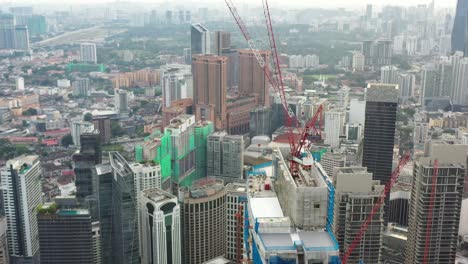 Fly-around-downtown-kuala-lumpur,-capturing-urban-landscape-with-dense-cityscape-full-of-high-rise-commercial-buildings-and-residential-apartments-with-structures-under-construction