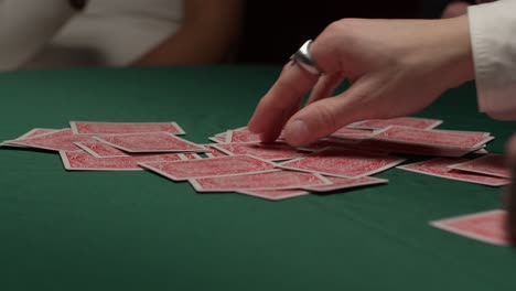 Eine-Gruppe-Von-Spielern-Zieht-In-Einem-Dunklen,-Stimmungsvollen-Casino-Karten-Aus-Einem-Stapel