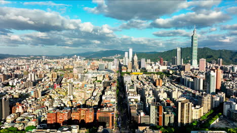 Vorwärtsflug-Aus-Der-Luft-über-Die-Schöne-Leuchtende-Stadt-Taipei-An-Bewölkten-Und-Sonnigen-Tagen,-Taiwan---Panoramablick-Mit-Wolkenkratzern-Und-101-Tower-Mit-Bergen-Im-Hintergrund