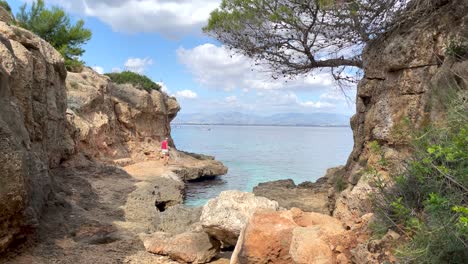 Women-Explores-Cliff-Formation-Area-At-Seaside,-Bella-Vista,-Mallorca,-Spain