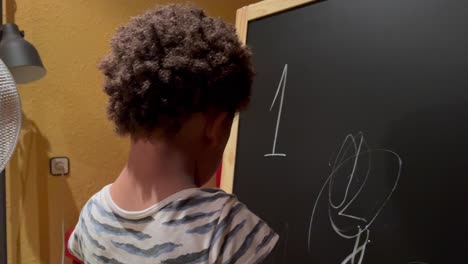 Schönes-Und-Exotisches-Zweijähriges-Afroamerikanisches-Kind,-Das-Zu-Hause-Seine-Ersten-Zeichnungen-Mit-Kreide-In-Einem-Brett-Macht