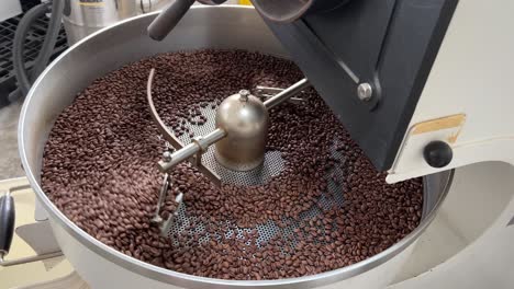 Aromatic-fresh-specialty-coffee-beans-spinning-on-cooling-and-mixing-tray-in-regular-speed-to-reduce-the-heat-evenly-after-roasting,-production-warehouse-factory-shot-of-food-and-beverage-industry