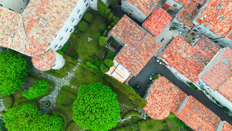 Aerial-top-down-shot-of-gourdon-village-with-colorful-rooftops-in-France-surrounded-by-green-forest-trees---Prores-drone-shot