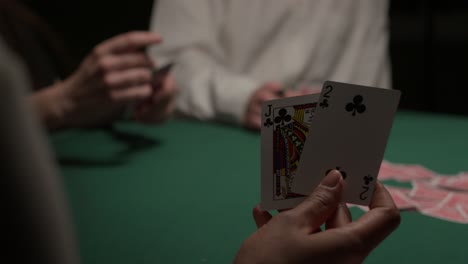 Eine-Spielerin-Zieht-Zwei-Karten-Und-Legt-Sie-Dann-Zurück-In-Ein-Dunkles,-Stimmungsvolles-Casino