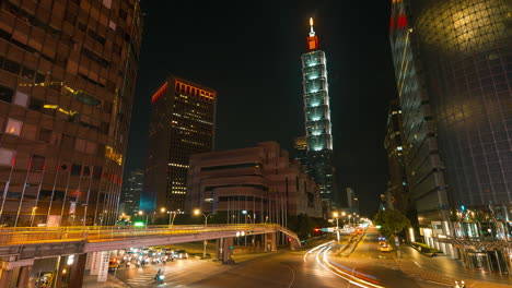 Toma-De-Lapso-De-Tiempo-Del-Tráfico-En-La-Carretera-En-El-Centro-De-La-Ciudad-De-Taipei-Con-La-Torre-101-En-El-Fondo---Luces-Intermitentes-Durante-La-Noche-Oscura-En-Taiwán