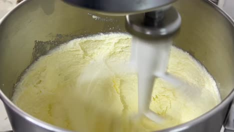 Handheld-shot-capturing-cake-batter-mixing-in-heavy-duty-electric-mixer-at-commercial-kitchen-setting