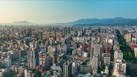 Sobrevuelo-Aéreo-Hermoso-Paisaje-Urbano-De-Taipei-Con-Rascacielos-Durante-El-Día-Soleado-Con-Niebla-Entre-Montañas-En-El-Horizonte---Centro-Con-Renai-Road-En-La-Mañana